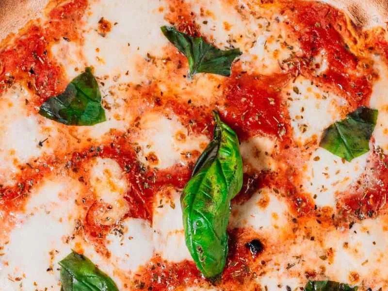 Close-up of a Margherita pizza with stringy mozzarella, fresh basil and a golden crust.